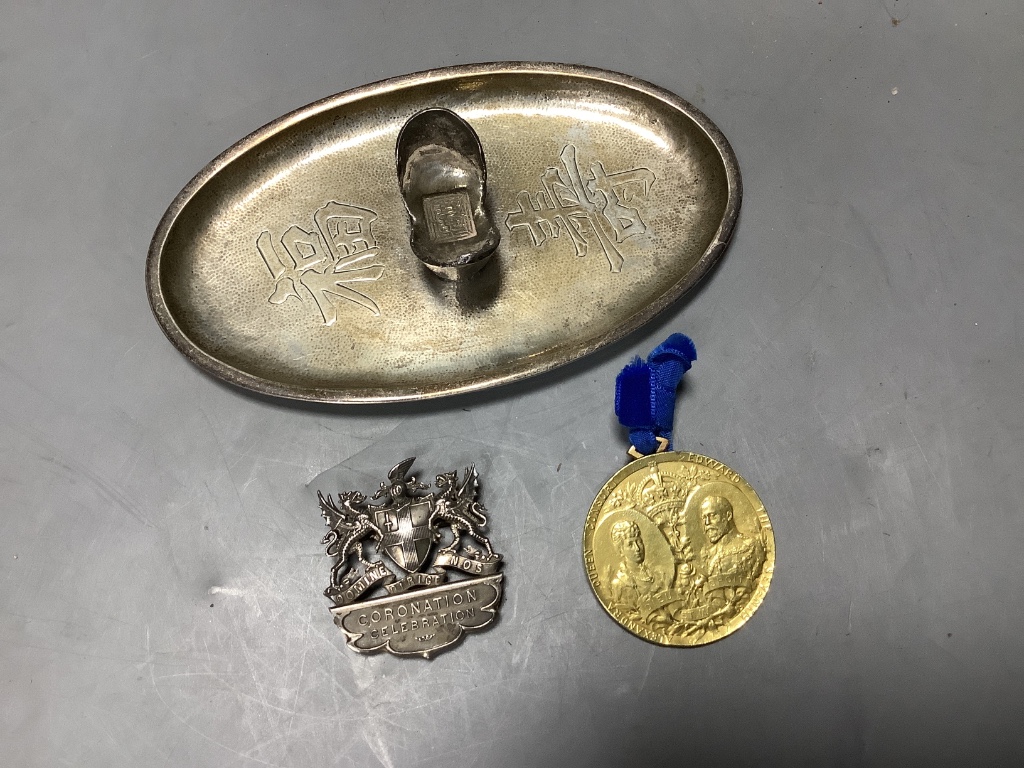 A Chinese white metal oval pen rest, 11.7cm and an Edwardian Coronation Celebration medallion.